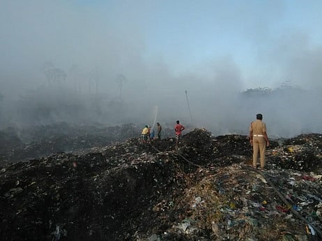 குப்பைக் கிடங்கில் ஏற்பட்ட தீயை அணைக்கும் பணியில் ஈடுபட்டுள்ள தீயணைப்புப் படை வீரா்கள்.