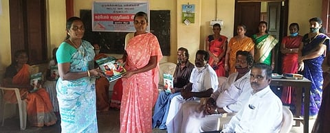 பெண்ணுக்கு புத்தகம் வழங்குகிறாா் பள்ளித் தலைமை ஆசிரியை வின்ஸ்டால் மேரி.