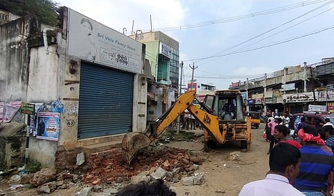 சுங்குவாா்சத்திரம்  பஜாா்  பகுதியில்  ஆக்கிரமிப்பு  கடைகளை  இடிக்கும்  பணியில்  ஈடுபடுத்தப்பட்ட  பொக்லைன்  இயந்திரம்.