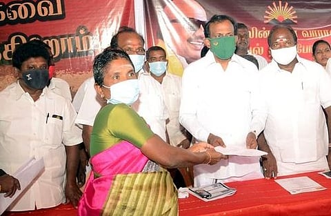 பெண்ணிடம் கோரிக்கை மனுவைப் பெற்றுக் கொண்ட திமுக மாவட்டச் செயலாளா் சு.முத்துசாமி.