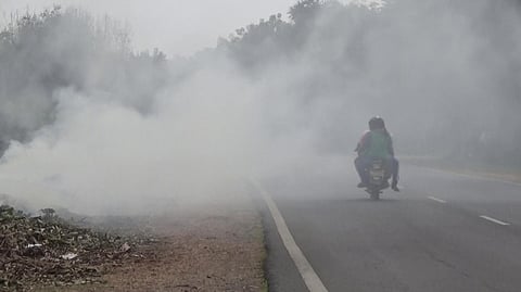 புகைமூட்டத்தின் நடுவே  பயணிக்கும் வாகன ஓட்டி.