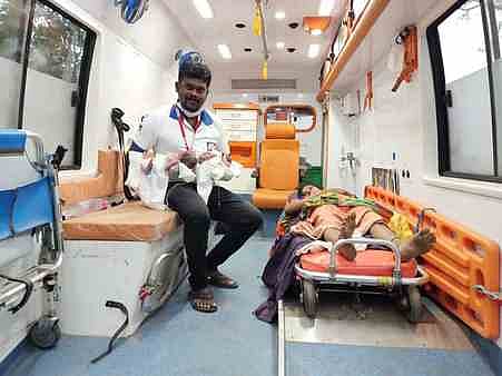 தாய் அமுதா, இரு குழந்தைகளுடன் ஆம்புலன்ஸ் மருத்துவ உதவியாளா் தேவராஜ்.