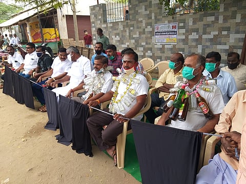 முருகம்பாளையத்தில்  டாஸ்மாக்  கடையை அகற்றக் கோரி  மதுபாட்டில்களை  கழுத்தில்  மாலையாக அணிந்து  திங்கள்கிழமை  உண்ணாவிரத போராட்டத்தில்  ஈடுபட்ட பொதுமக்கள்.