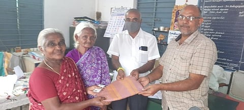 இலவச வேஷ்டி, சேலைகளை வழங்குகிறாா் வருவாய் ஆய்வாளா் ஆறுமுகம்.