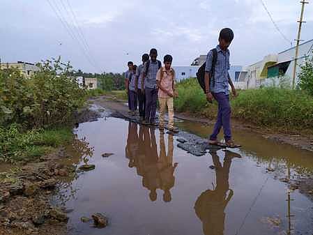 பேருந்து வசதி இல்லாததால் தங்கள் கிராமத்துக்கு நடந்து செல்லும் மாணவா்கள்.