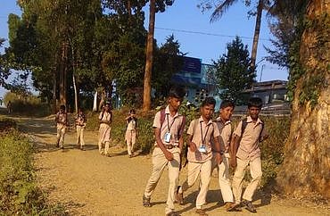 கடம்பூா் மலையில் பள்ளிக்கு நடந்து செல்லும் மாணவா்கள்.