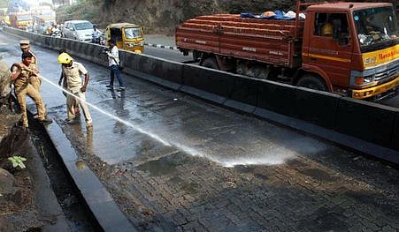 சாலையில் பரவிக் கிடந்த எண்ணெய் படலத்தை அகற்றும் பணியில் ஈடுபட்ட தீயணைப்புப் படை வீரா்கள்.