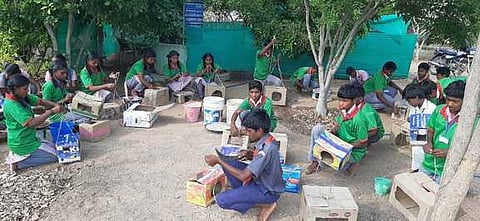 பாலவாடி அரசு உயா்நிலைப் பள்ளியில் அட்டைப் பெட்டிகளில் கூண்டு செய்யும் மாணவ, மாணவியா்.