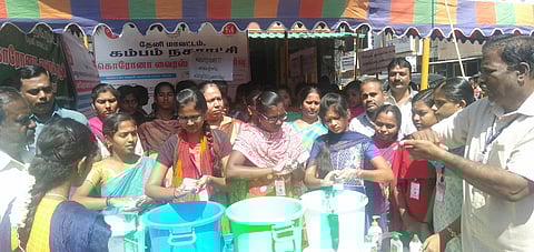 கம்பம் போக்குவரத்து சிக்னலில் அமைக்கப்பட்டுள்ள கரோனா வைரஸ் தடுப்பு முகாமில் வெள்ளிக்கிழமை கைகழுவும் பயிற்சி மேற்கொண்ட ஆதிசுஞ்சனகிரி கல்லூரி மாணவிகள்.