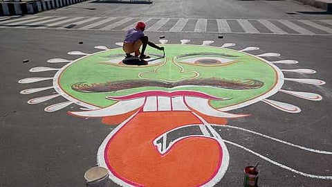 கரூா் பேருந்துநிலைய ரவுண்டானா பகுதியில் கரோனா ஓவியம் வரைகிறாா் ஓவியா் சதாசிவம்.