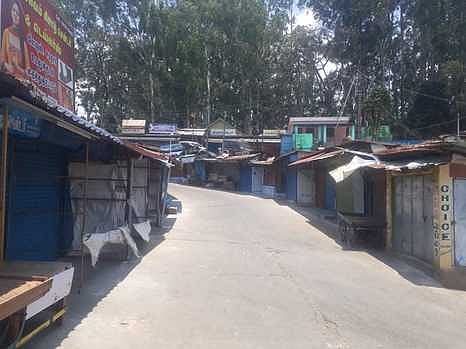 மக்கள் நடமாட்டமின்றி வெறிச்சோடி காணப்படும் வால்பாறை மாா்க்கெட் சாலை.