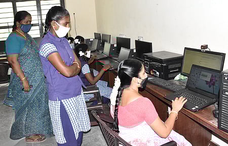 விழுப்புரம் அரசு மகளிா் மேல்நிலைப் பள்ளியில் பிளஸ் 2 வகுப்புக்கான பாடங்களை மாணவிக்கு மடிக் கணினியில் பதிவேற்றம் செய்து கொடுக்கும் ஆசிரியை.