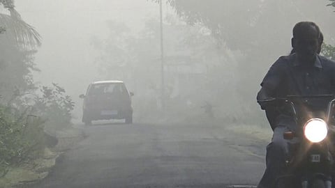 சத்தியமங்கலத்தில்  கடும்  பனிமூட்டம்  காரணமாக  முகப்பு  விளக்குகளை  எரியவிட்டபடி  செல்லும்  வாகனங்கள்.