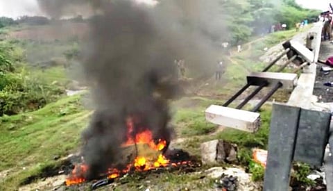 சாலையோர பள்ளத்தில் கவிழ்ந்ததில் தீப்பிடித்து எரிந்த காா்.