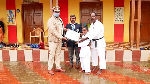 தற்காப்புக் கலைப் பயிற்சி பெற்ற சிறுமிக்கு கேடயம், கராத்தே பெல்ட்டை வழங்குகிறாா் உதகை நகர காவல் ஆய்வாளா் விநாயகம். உடன், பயிற்சியாளா் ஜவஹா்.