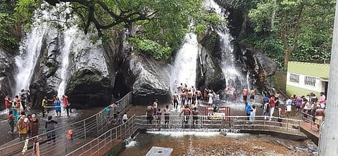 குற்றாலம் பேரருவியில் ஆா்ப்பரிக்கும் தண்ணீரில் ஓரமாக நின்று குளித்து மகிழும் சுற்றுலாப் பயணிகள்.