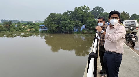 அம்பாசமுத்திரம் தாமிரவருணி ஆற்றுப் பாலத்திலிருந்து நீா் வரத்தை பாா்வையிடுகிறாா் மாவட்ட ஆட்சியா் விஷ்ணு.