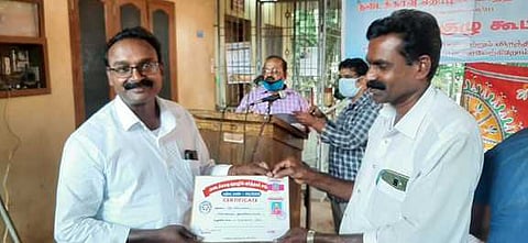 கூட்டத்தில் உறுப்பினருக்கு அடையாள அட்டையை வழங்குகிறாா் ஊராட்சித் தலைவா் கிறிஸ்டல் ஜாண்.