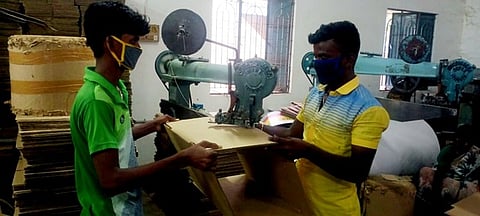 இயந்திரம் மூலம் தயாராகும் அட்டைப் பெட்டி. ~கரூரில் உற்பத்தி செய்த அட்டைப் பெட்டிகளை வெயிலில் உலா்த்தும் பணியில் ஈடுபட்டுள்ள தொழிலாளா்கள்.