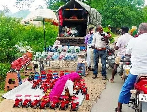 அயோத்தியாப்பட்டணம் அருகே சாலையோரத்தில் விற்பனைக்கு அடுக்கி வைக்கப்பட்டுள்ள பொம்மைகளை ஆர்வத்தோடு வாங்கும் வழிபோக்கர்கள்.