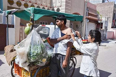காய்கறி விற்பனையாளர் ஒருவருக்கு கரோனா தடுப்பூசி செலுத்தும் சுகாதார பணியாளர்.