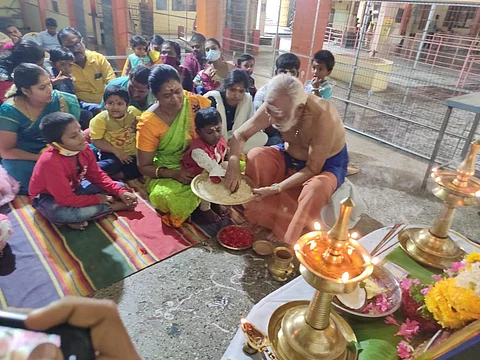 சரஸ்வதி பூஜையையொட்டி கோயிலின் குருக்கள் ஆர். சிவதாஸ், பச்சரிசியில் குழந்தைகளின் விரலைக் கொண்டு ஓம் ஹரி ஸ்ரீ கணபதே நமக என எழுத செய்தார்.