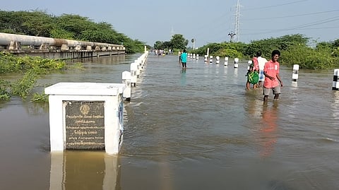 ராமநாதபுரம் அருகே வெள்ளிக்கிழமை வெள்ளத்தால் மூழ்கிய காவனூா் மேம்பாலத்தில் நடந்து சென்ற பொதுமக்கள்.