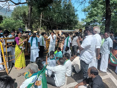 பென்னிகுயிக் மண்டபம் செல்லும் வழியில் தரையில் அமர்ந்து போராட்டம் நடத்தும் 5 மாவட்ட விவசாயிகள்.