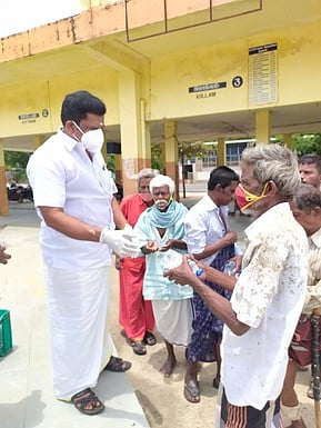 பேருந்து நிலையத்தில் தங்கியிருந்தவா்களுக்கு உணவுப் பொட்டலங்களை வழங்குகிறாா் மணிகண்டன்.