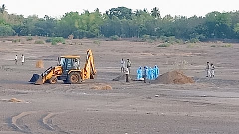 மயானத்திலிருந்து தோண்டியெடுக்கப்பட்ட கரோனா நோயாளியின் சடலத்தை திட்டக்குடி வெள்ளாற்றின் நடுப் பகுதியில் புதைக்கும் பணியில் ஈடுபட்ட அலுவலா்கள்.