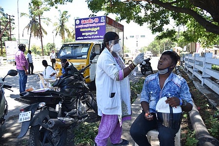 வாகன ஓட்டியிடம் பரிசோதனை மேற்கொள்ளும் சுகாதாரப் பணியாளா்கள்.