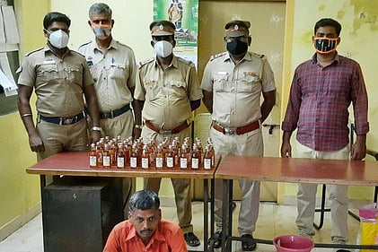 மதுப் புட்டிகளை பறிமுதல் செய்து கைது செய்யப்பட்ட ஏழுமலை.