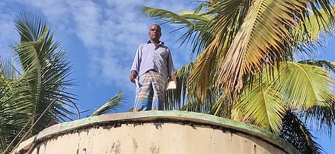 நாச்சினாம்பட்டியில் மேல்நிலை நீா்த்தேக்கத் தொட்டி மீது ஏறி ஞாயிற்றுக்கிழமை போராட்டத்தில் ஈடுபட்ட விவசாயி முருகன்.