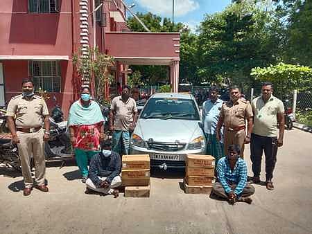 பறிமுதல் செய்யப்பட்ட காா், மதுப் புட்டிகளுடன் கைது செய்யப்பட்ட லெமின், சரண்ராஜ்.