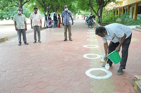 நாமக்கல் தெற்கு அரசு ஆண்கள் மேல்நிலைப் பள்ளியில் மாணவா்கள் சமூக இடைவெளிக்காக வட்டமிடும் ஊழியா்கள்.