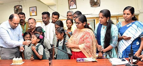 அரசுப் பள்ளி மாணவிகளுக்கு கேக் ஊட்டுகிறாா் மாவட்ட ஆட்சியா் ஹெச்.கிருஷ்ணனுண்ணி.