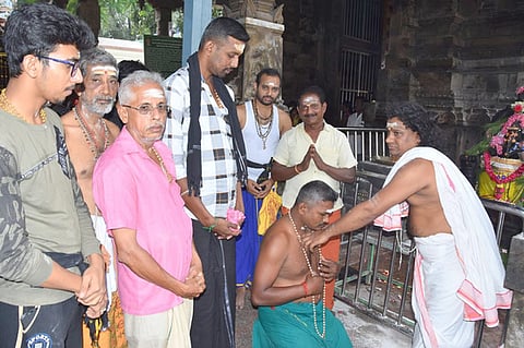 பழனி திருஆவினன்குடி கோயிலில் வியாழக்கிழமை காா்த்திகை முதல் நாளை முன்னிட்டு விரதம் தொடங்கிய பக்தருக்கு மாலை அணிவிக்கும் குருக்கள்.