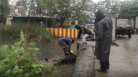 தண்ணீரின் அளவு உயராத வண்ணம் மணல் மூட்டைகளை அடுக்கி வரும் மாநகராட்சி ஊழியர்கள்.