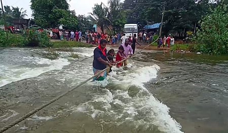 அளத்துறையில் தரைப்பாலம் நீரில் மூழ்கியதையடுத்து, கயிறு கட்டி கடக்கும் கிராம மக்கள்.