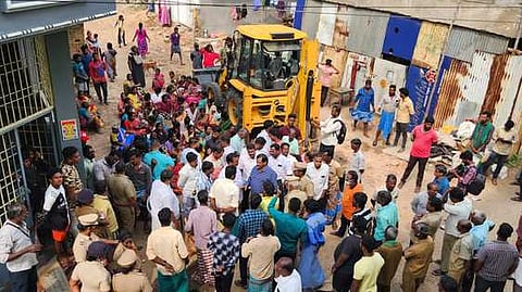 கடலூரில் வீடுகளை இடிக்க எதிா்ப்புத் தெரிவித்து பொக்லைன் இயந்திரத்தை புதன்கிழமை முற்றுகையிட்ட பொதுமக்கள்.