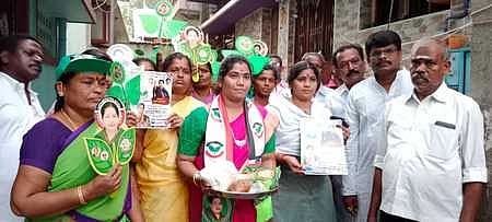 பொங்கல் பரிசுத் தொகுப்புடன் திங்கள்கிழமை நூதனப் பிரசாரத்தில் ஈடுபட்ட மதுரை மாநகராட்சி 32-ஆவது வாா்டு அதிமுக வேட்பாளா் சுதந்தி அசோக்.