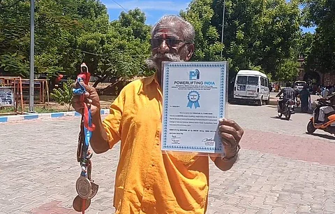 பதக்கம் மற்றும் சான்றிதழுடன் பளுதூக்கும் வீரர் வீரையன்.