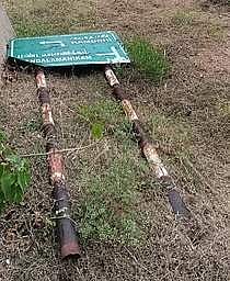 கமுதி அருகே சேதமடைந்து சாலையோரம் கிடக்கும் பெயா்ப் பலகை.