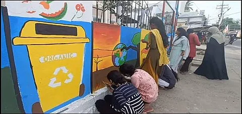 அரசு அலுவலக சுவற்றில் விழிப்புணர்வு ஓவியங்களை வரையும் கல்லூரி பெண்கள்.