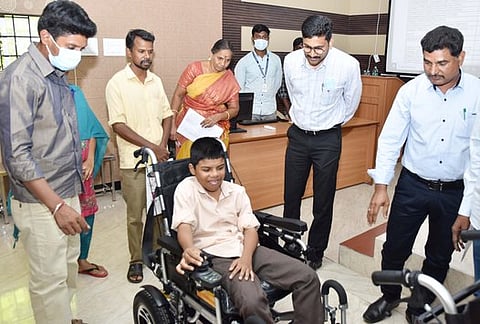 ‘மாற்றுத் திறனாளி சிறுவனுக்கு போட்டரியால் இயங்கும் வீல் சேரை வழங்குகிறாா் மாவட்ட ஆட்சியா் எஸ்.வினீத்.