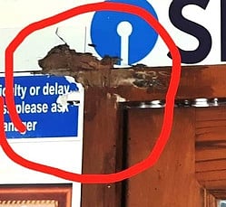 துப்பாக்கி வெடித்ததில் சேதமடைந்த வங்கியின் சுவா்.