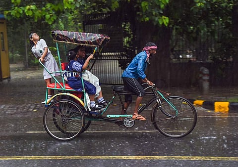 தலைநகர் தில்லியில் பலத்த சூறைக்காற்றுடன் மழை பெய்து வருவதால் மழையில் நனைந்தபடி ரிக்ஷாவில் செல்லும் பள்ளி மாணவர்கள்.