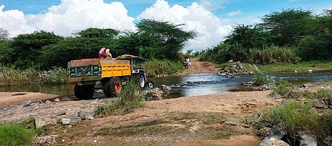 திருவாளந்துறை- கல்பூண்டி இடையே மேம்பாலம் அமைக்கும் பணி கிடப்பில் உள்ள நிலையில் வெள்ளாற்றைக் கடந்து சென்ற டிராக்டா்.
