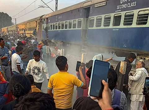 தீப்பற்றிய ரயில் பெட்டியைச் சூழ்ந்து நிற்கும் பயணிகள்