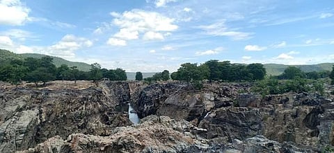 காவிரி ஆற்றில் நீர்வரத்து சரிந்துள்ளதால், நீரின்றி பாறை திட்டுகளாக காணப்படும் ஒகேனக்கல் ஐவா்பாணி.